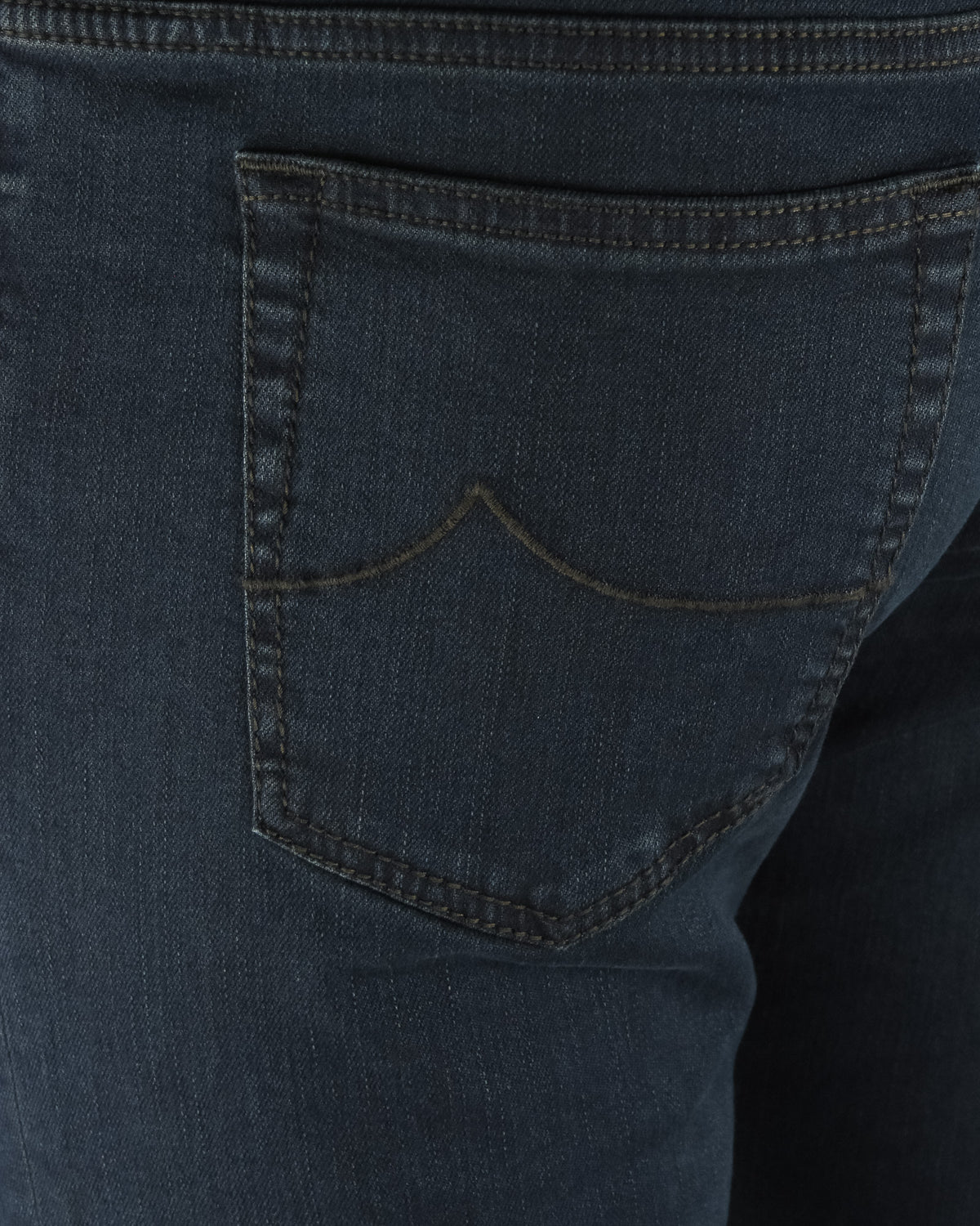 Dark blue denim jeans front pocket detail with curved yoke stitching.