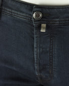 Dark blue stretch denim jeans waist with logo button and inner pocket tab.