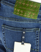 Back pocket area with hanging white tag and black clip on dark blue denim.