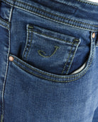 Back denim pocket with green contrast stitching and small embroidered logo detail.