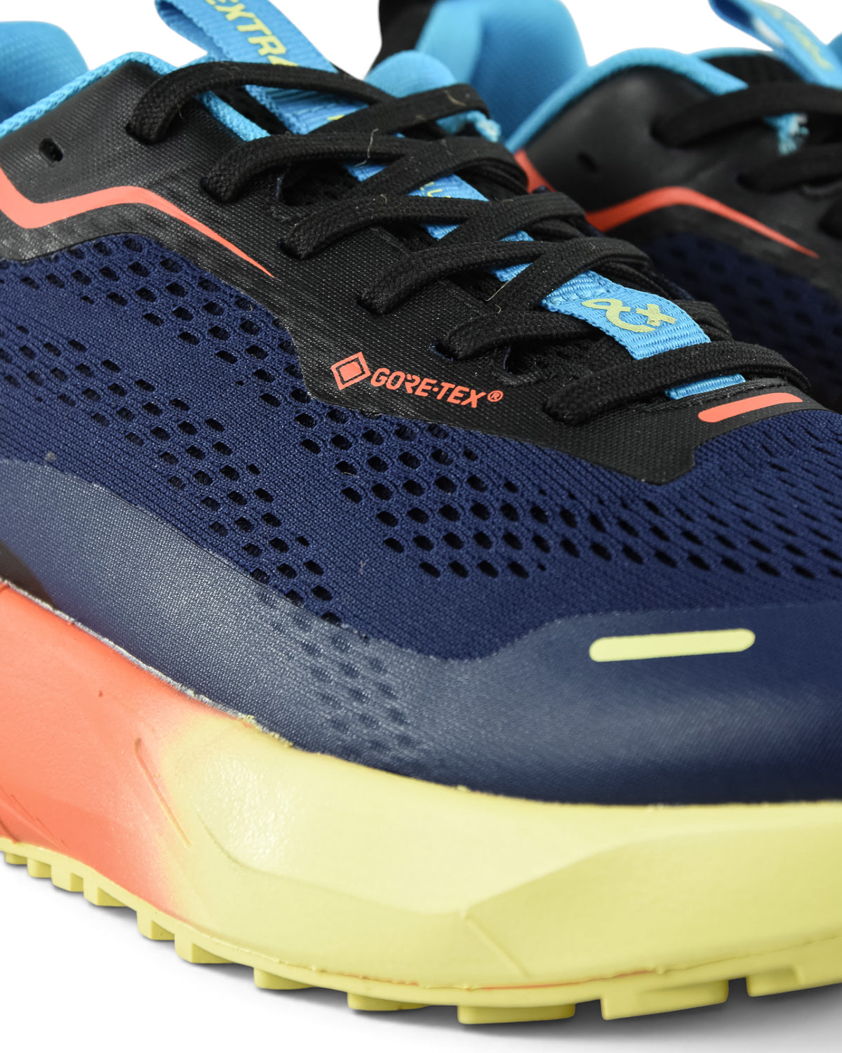 Waterproof running shoe close-up: navy mesh upper with black laces, red logo trim, blue details.