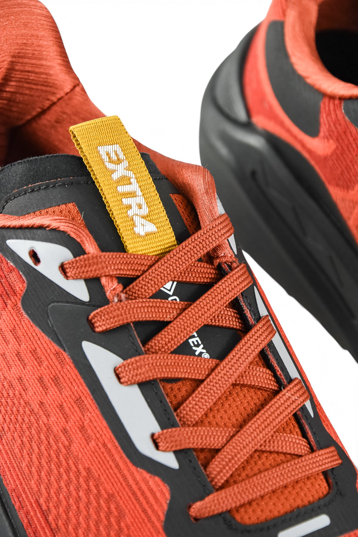 Rust orange running shoes with orange laces and yellow logo tab, black heel