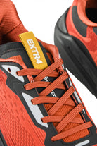 Rust orange running shoes with orange laces and yellow logo tab, black heel