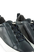 Close-up of navy leather low-top sneaker with lace-up panel and metal toggle clasp.