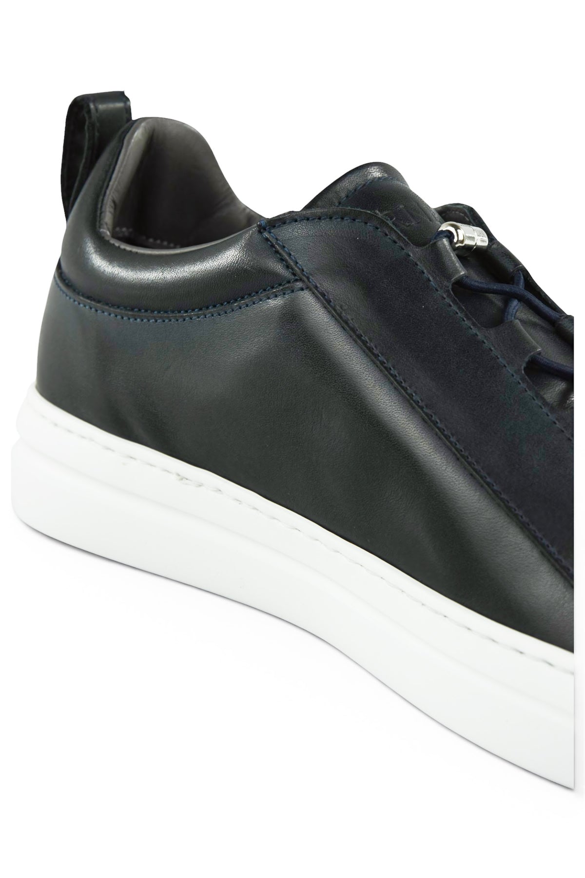 Navy leather low-top sneaker side with metal toggle and white rubber sole.