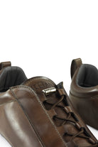 Brown leather low-top trainer tongue detail with metal toggle and lace eyelets