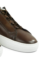 Brown leather low-top trainer close-up with lace-up, stitching seams, and white midsole
