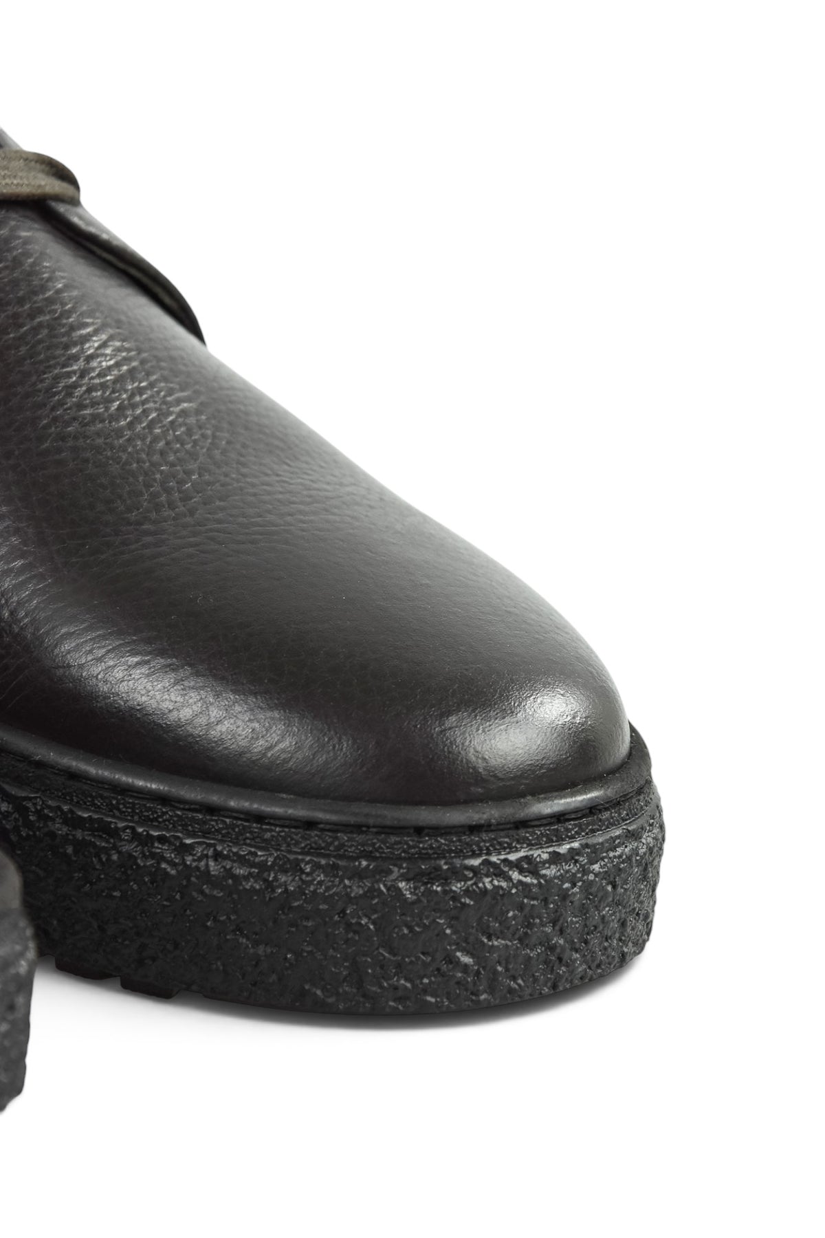 Close-up of dark leather ankle boot toe with textured platform sole