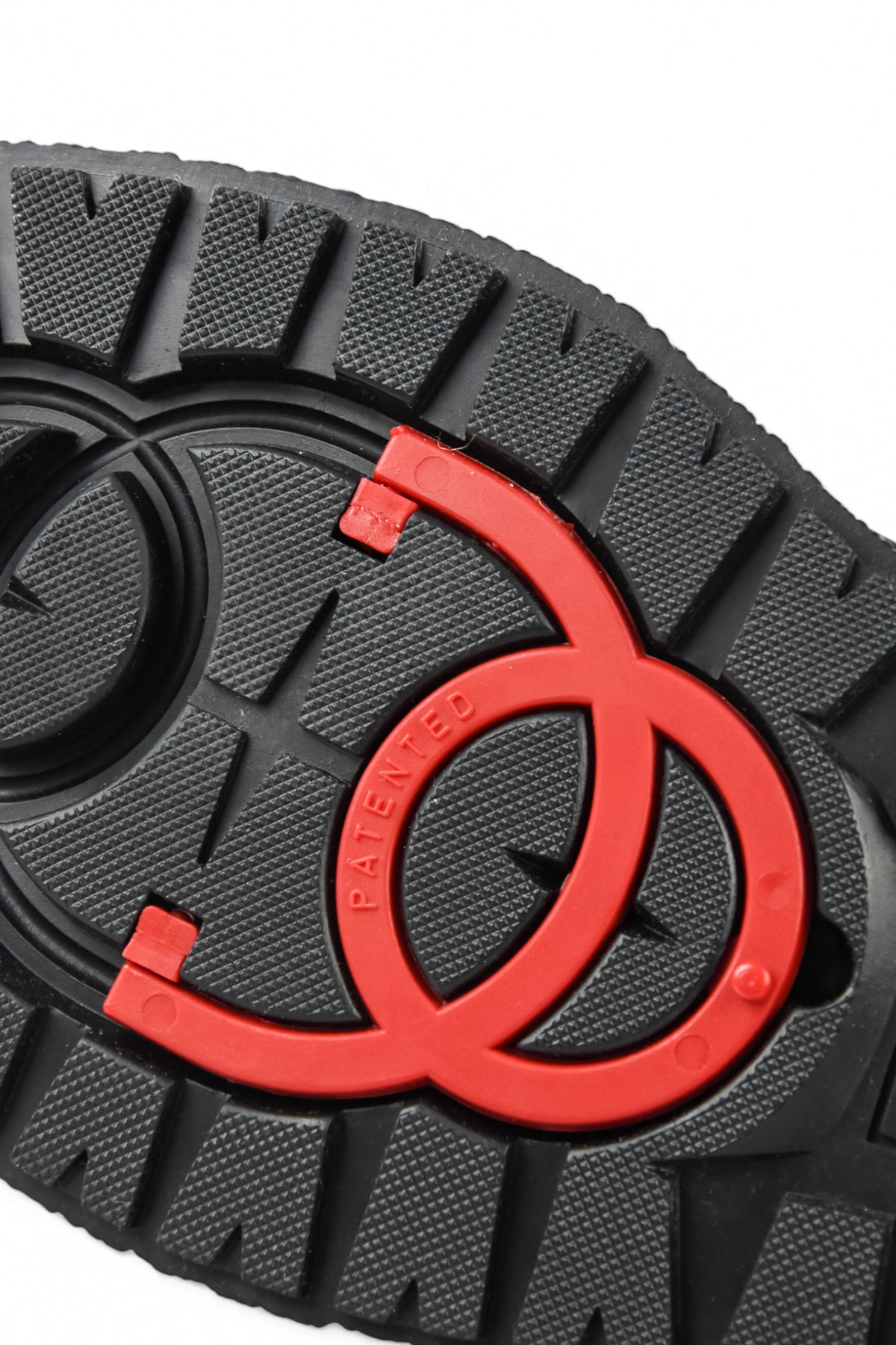 Detailed view of grippy boot tread with red and black circular inserts