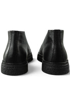 Back view of black leather ankle boots showing stacked heel and tread sole.