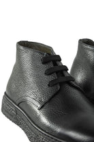 Side view of black leather lace-up ankle boot with textured sole edge.