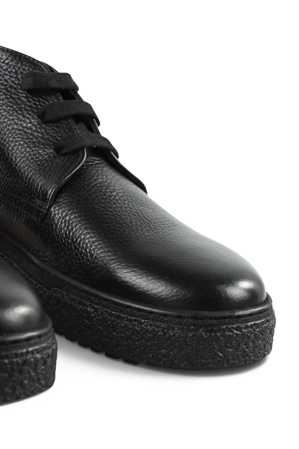 Close-up side view of black leather lace-up ankle boot with tread sole.