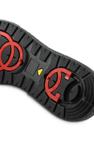 Black ankle boot outsole with red circular grip plate and small yellow marker