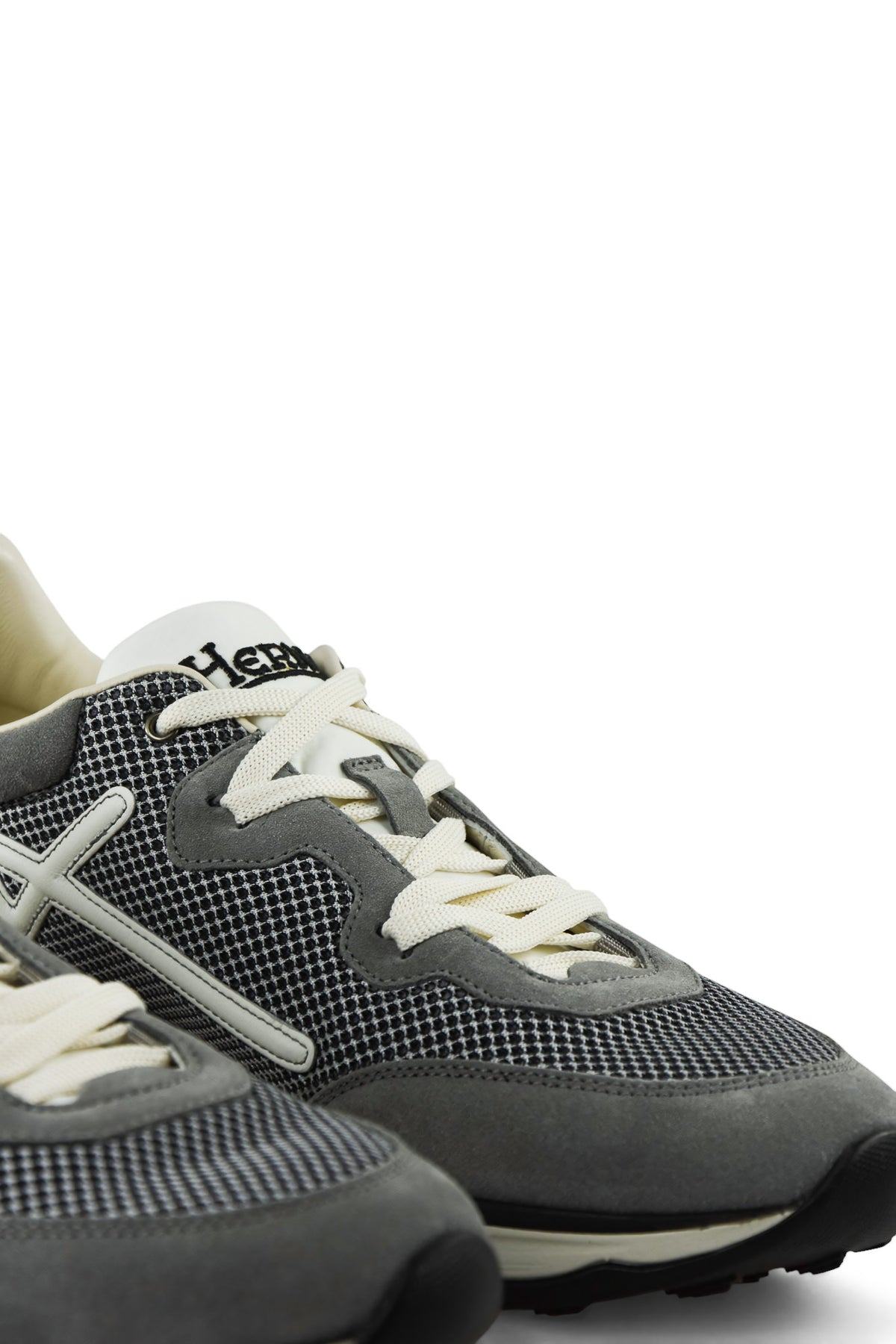 Grey low-top trainers with white laces, side stripes, and chunky black toe