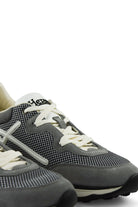 Grey low-top trainers with white laces, side stripes, and chunky black toe