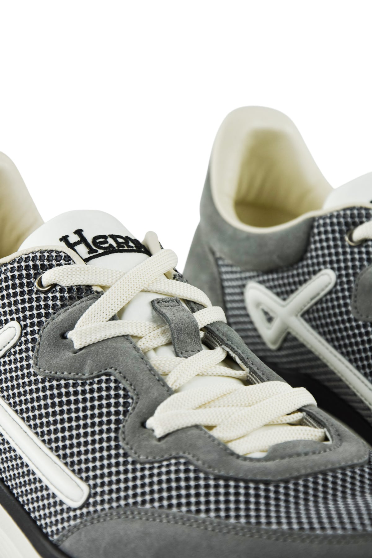Grey trainers close-up with white lace-up, heel suede panel, and knit texture