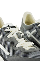 Grey trainers close-up with white lace-up, heel suede panel, and knit texture