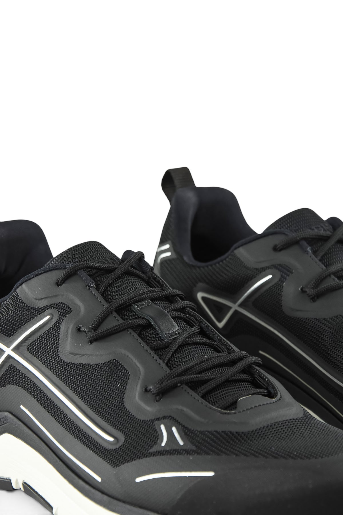 Close-up of black lace-up mesh trainers with side logo and white accent midsole