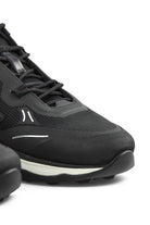 Front-side close-up of black mesh trainer with lace-up closure and sculpted sole