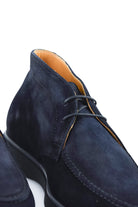 Blue suede chukka desert boot with lace-up front and tan lining at collar.