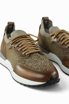 Two tan lace-up trainers showing knit uppers, brown leather toe trim, and white soles
