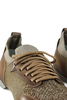 Close-up of tan lace-up knit trainer with brown leather lace placket and textured upper