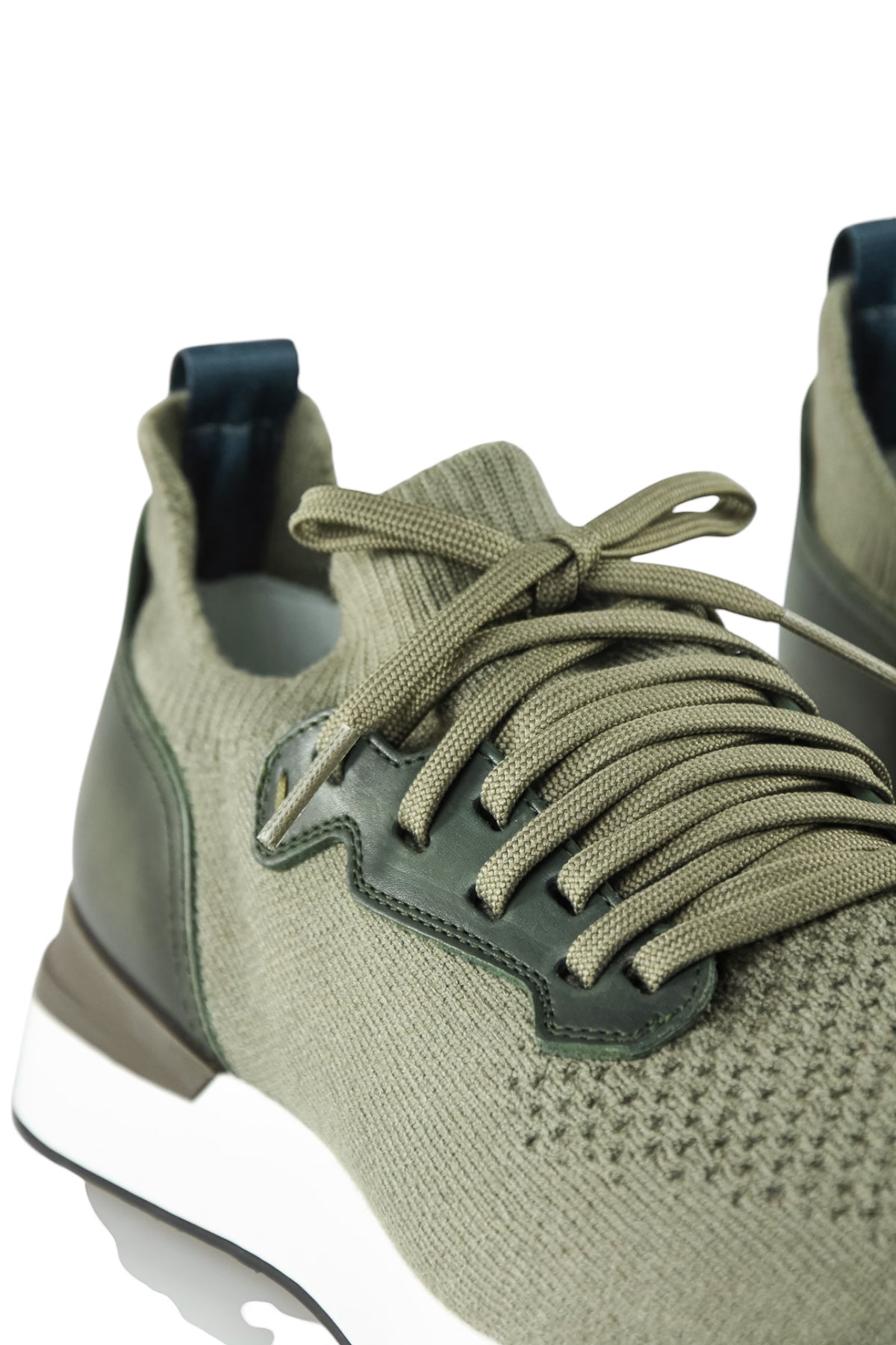 Khaki lace-up sneaker close-up with knit texture, leather quarter panel, and dark lining