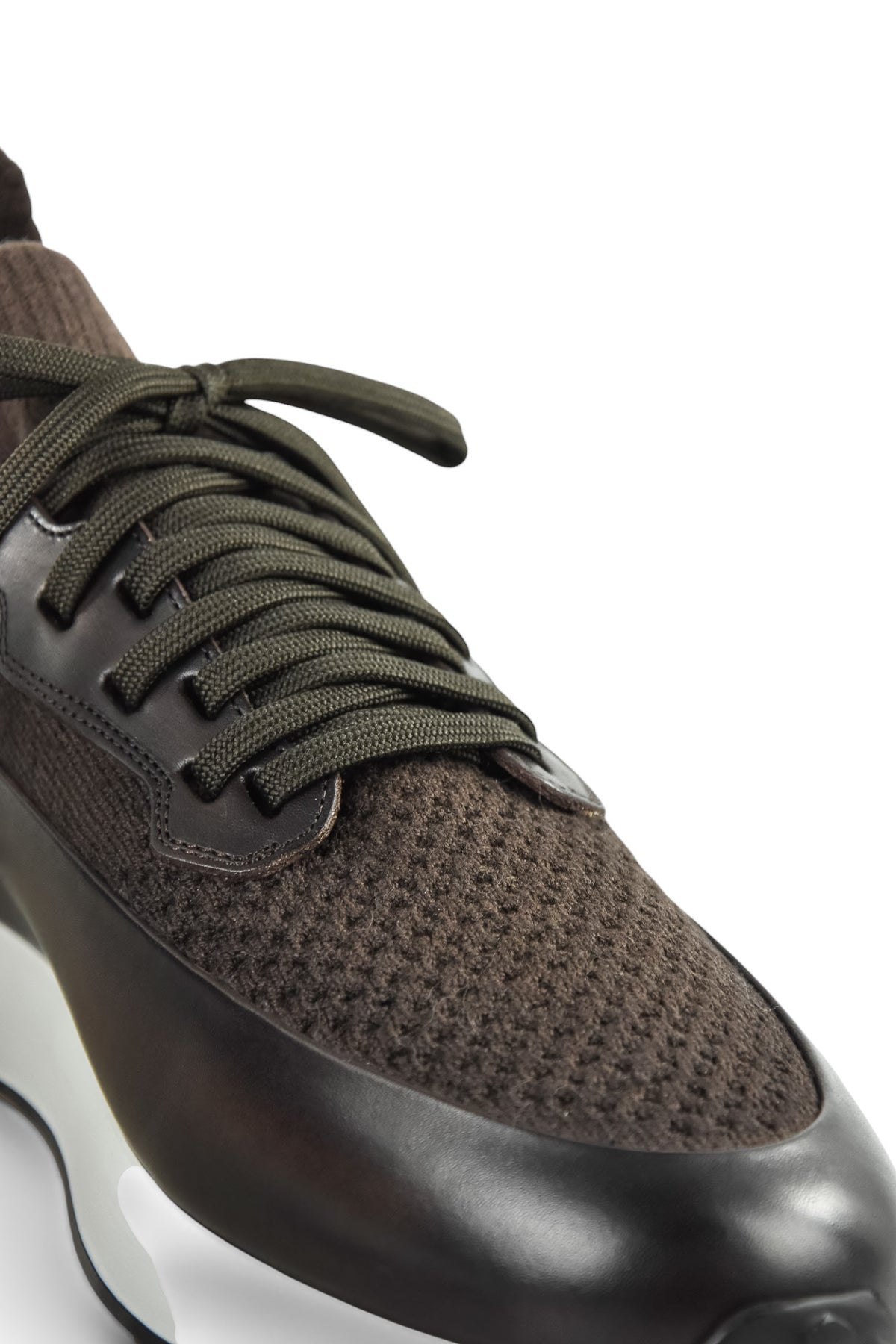 Close-up side of dark brown knit and leather lace-up trainer with textured upper.