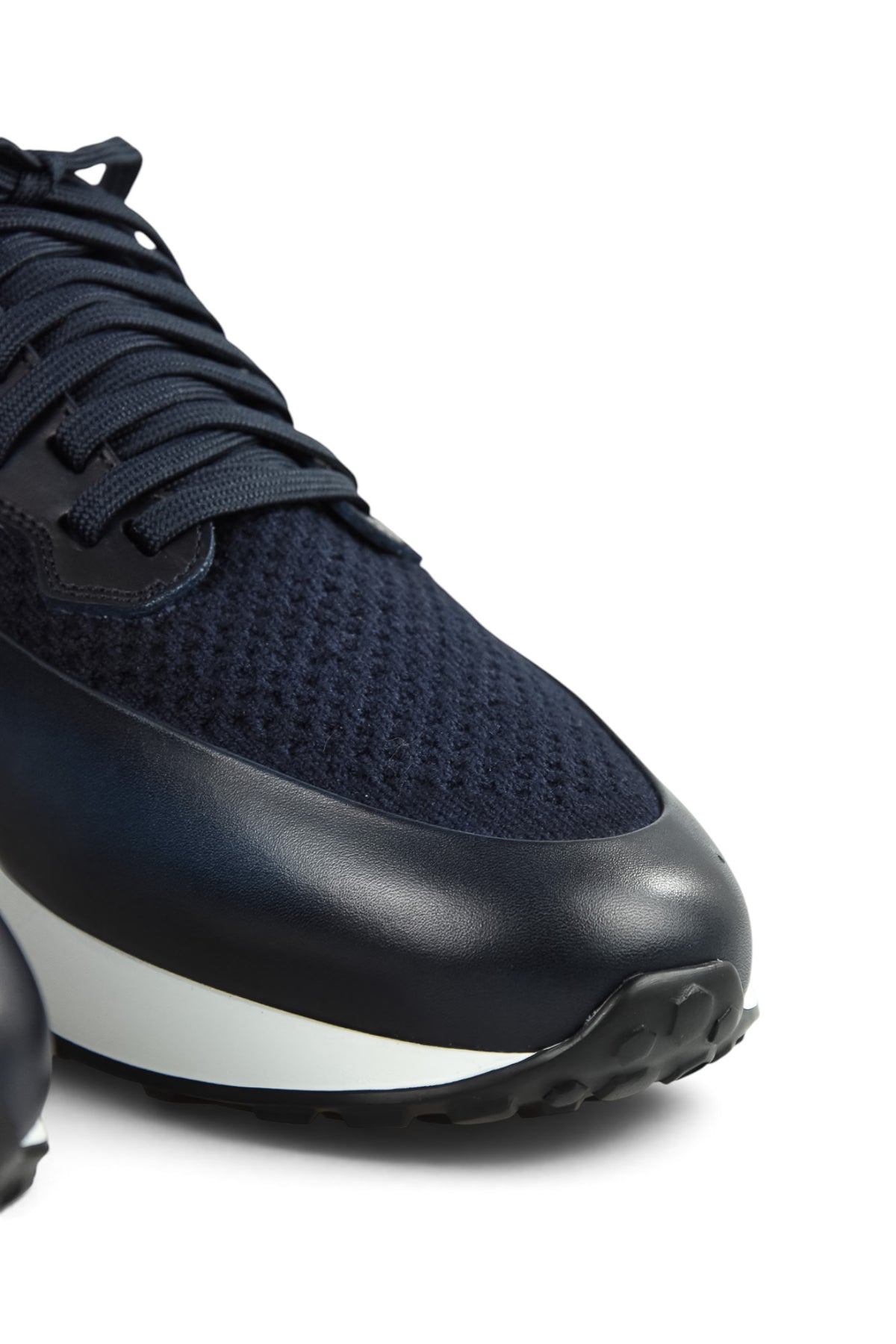 Close-up side view of dark blue knitted trainers with lace-up stitching and white midsole