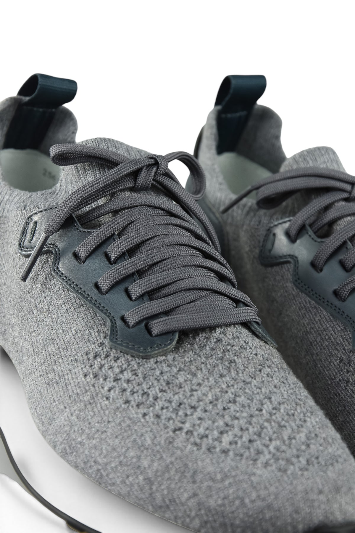 Close-up of grey knit upper with lace-up eyelets and leather side detail
