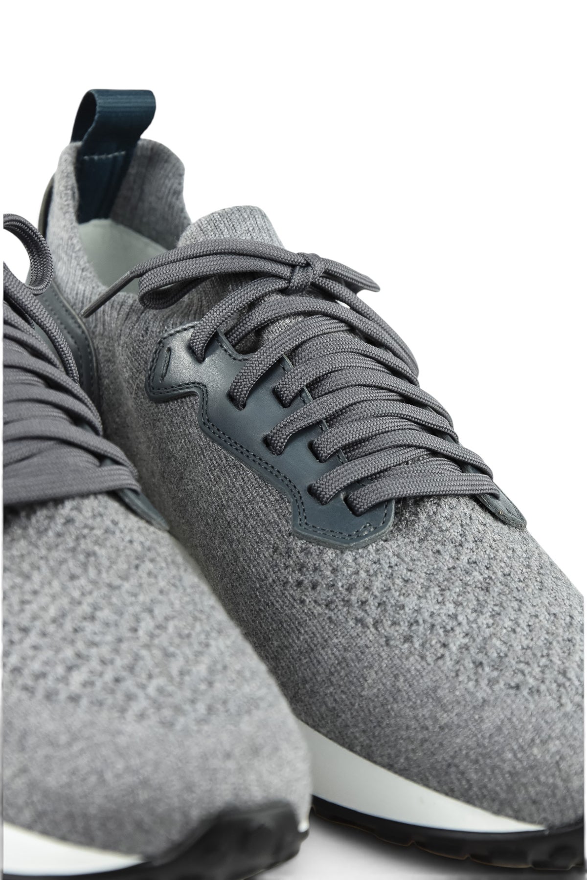 Detail view of grey lace-up knit trainers with dark overlay and textured fabric