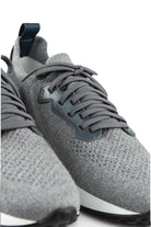 Detail view of grey lace-up knit trainers with dark overlay and textured fabric