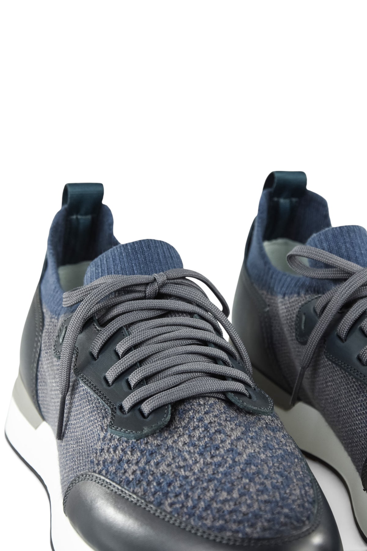 Close-up of men's lace-up trainer upper with grey knit texture and dark leather trim