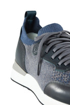 Close-up of men's trainer quarter: grey knit upper, dark leather lace panel, side view
