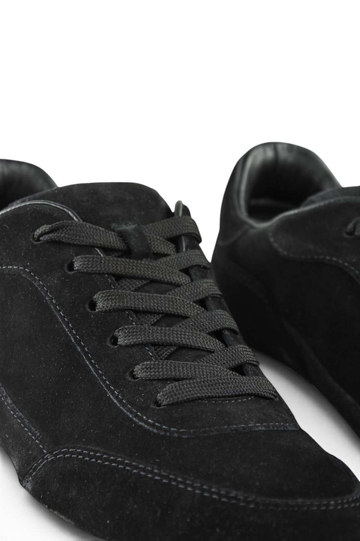 Close-up of black suede lace-up sneaker with stitched panel details