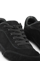 Close-up of black suede lace-up sneaker with stitched panel details