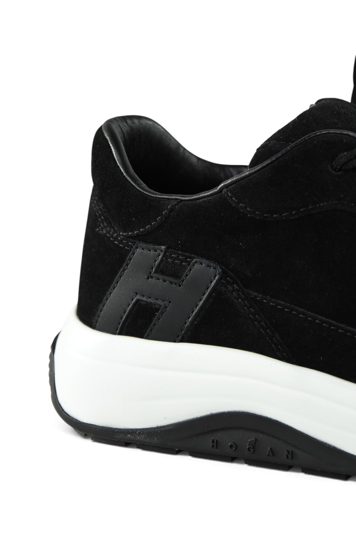 Close-up of black suede heel and side H logo with white sole