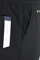 Black technical stretch pants with “DYNAMIC” fabric label close-up