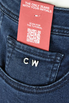 Dark blue jeans pocket with CW initials and red tag instructions with QR code