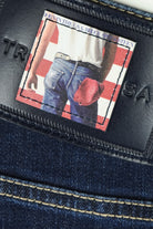 Dark blue jeans label patch with photo graphic and stitched border detail.
