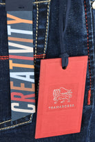 Red hangtag on dark blue jeans pocket with Tramarossa logo and hanging string.
