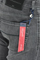 Dark grey denim jeans with visible branded hang tag and belt loop detail