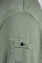 Olive green sleeve lens patch with button closure and stitched flap