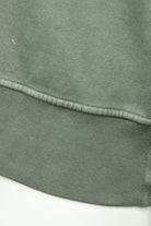 Olive green sweatshirt hem with contrast-stitched edge and brushed fleece