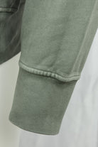 Olive green ribbed sweatshirt cuff with contrast-stitched seam