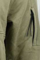 Olive green sleeve pocket detail with black drawcord grommets