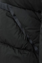 Close-up of black padded jacket interior with diagonal strap and zip pull