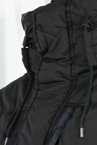 Black hooded padded jacket close-up with adjustable hood cords and zip