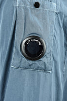Blue overshirt with circular C.P. Company lens badge on chest pocket