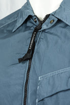 Blue overshirt collar with black zipper tape and gold button detail